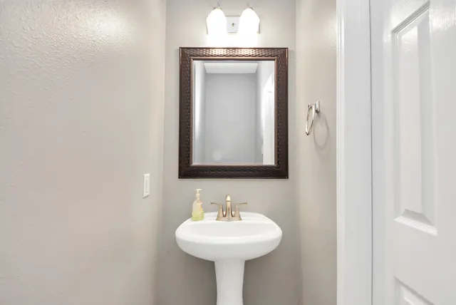 a view of a hallway with a sink and a mirror