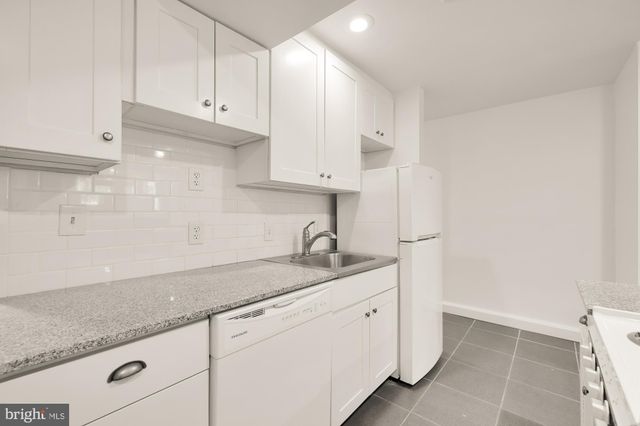 a kitchen with granite countertop white cabinets and a sink