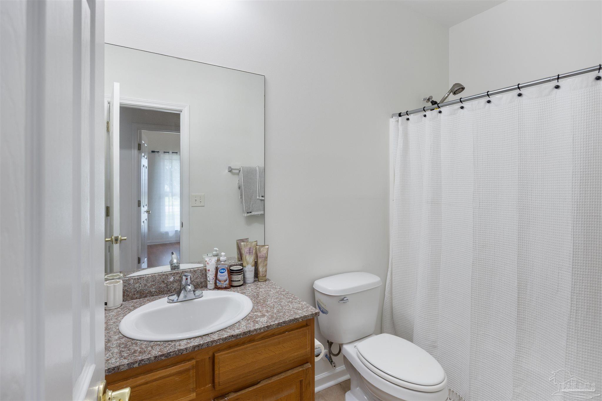 6887 Crimson Ridge Street Gulf Shores, AL 36542 - Photo 26 of 37 a bathroom with a granite countertop sink toilet a mirror and shower