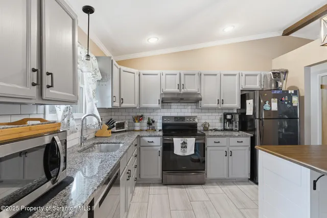 a kitchen with stainless steel appliances granite countertop a stove top oven a sink dishwasher and a refrigerator with wooden cabinets