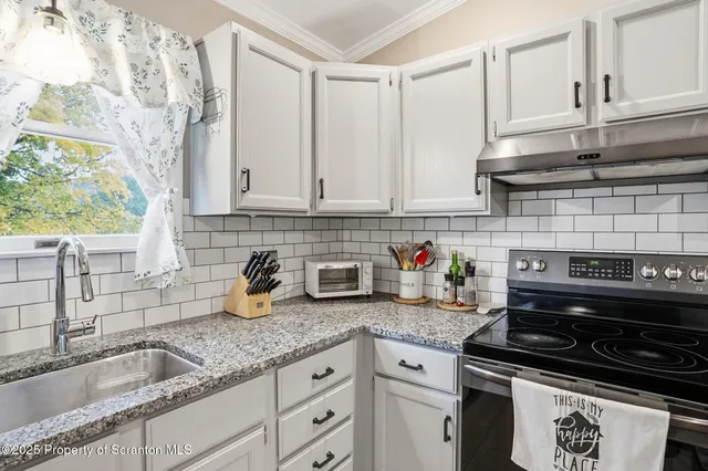 a kitchen with granite countertop a sink stove and cabinets