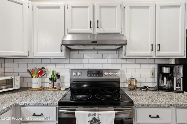 a kitchen with granite countertop a stove sink and cabinets