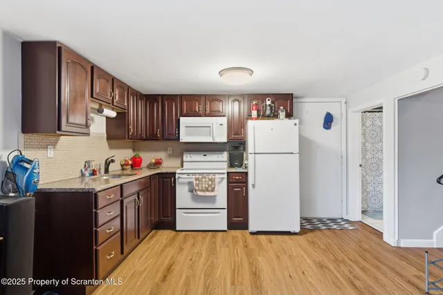 a kitchen with granite countertop a refrigerator stove top oven and sink