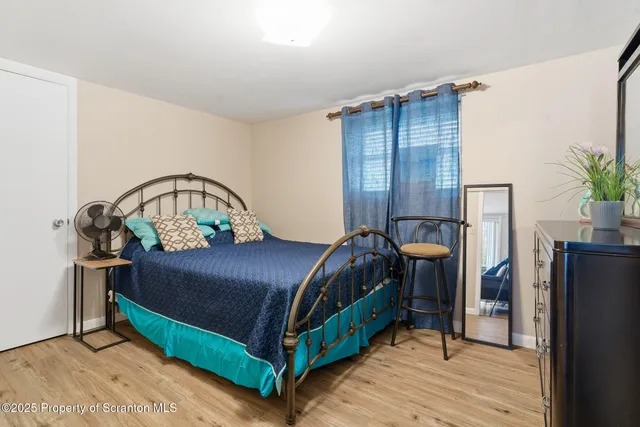 a bedroom with a bed table flowerpot and a window