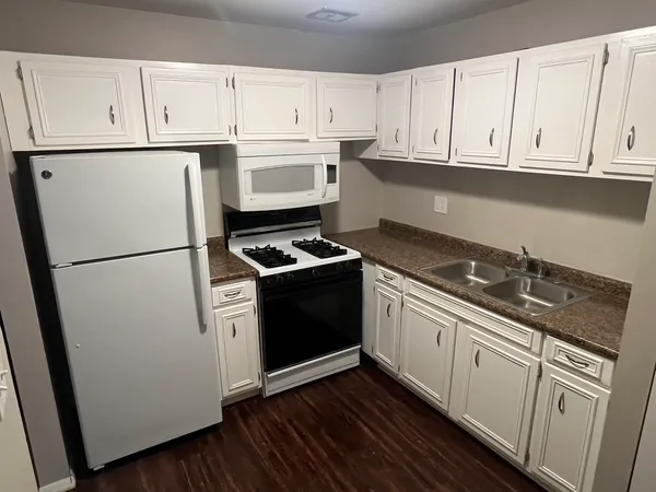 a kitchen with granite countertop white cabinets and white appliances