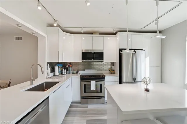 a kitchen with white cabinets and stainless steel appliances