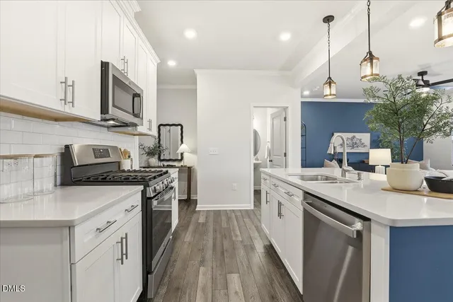 a kitchen with stainless steel appliances a sink cabinets and wooden floor
