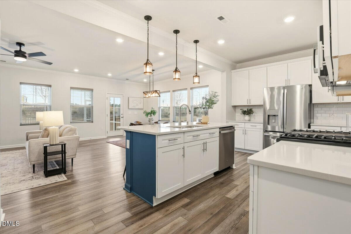 5052 Tura Street Raleigh, NC 27610 - Photo 4 of 47 a kitchen with stainless steel appliances kitchen island granite countertop a refrigerator a oven a stove and white cabinets with wooden floor