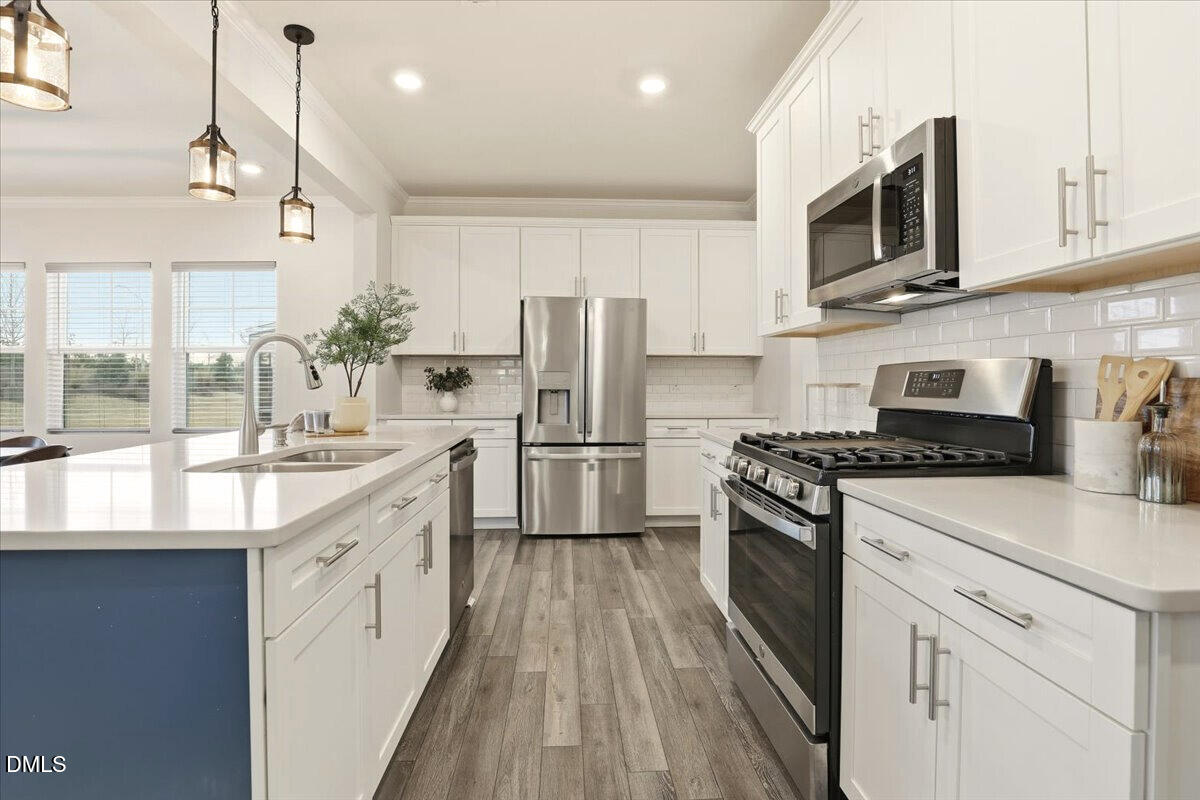 5052 Tura Street Raleigh, NC 27610 - Photo 5 of 47 a kitchen with stainless steel appliances granite countertop white cabinets a sink a stove a refrigerator and island with wooden floor