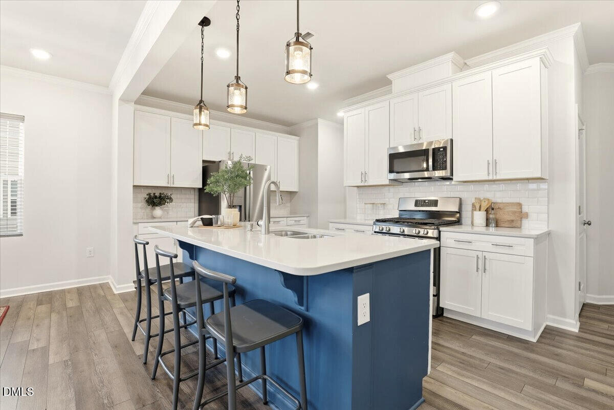 5052 Tura Street Raleigh, NC 27610 - Photo 6 of 47 a kitchen with kitchen island granite countertop a sink cabinets and wooden floor
