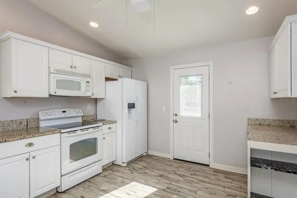 a kitchen with white cabinets and white appliances