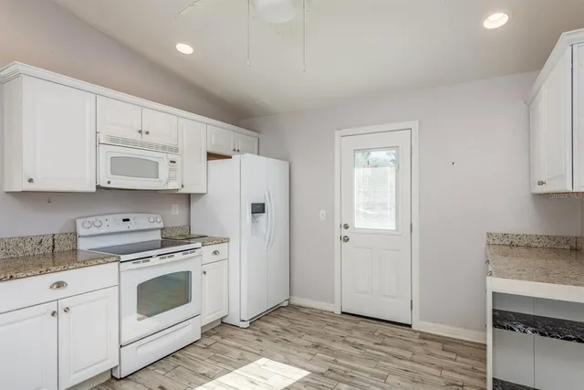 a kitchen with white cabinets and white appliances