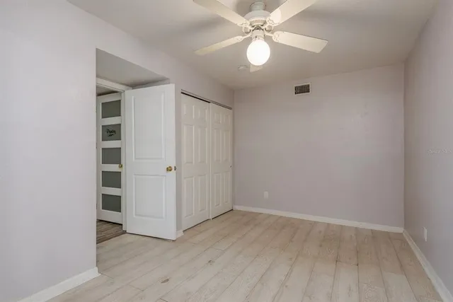 an empty room with wooden floor chandelier fan and closet