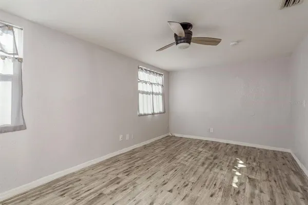 a view of empty room with wooden floor and fan