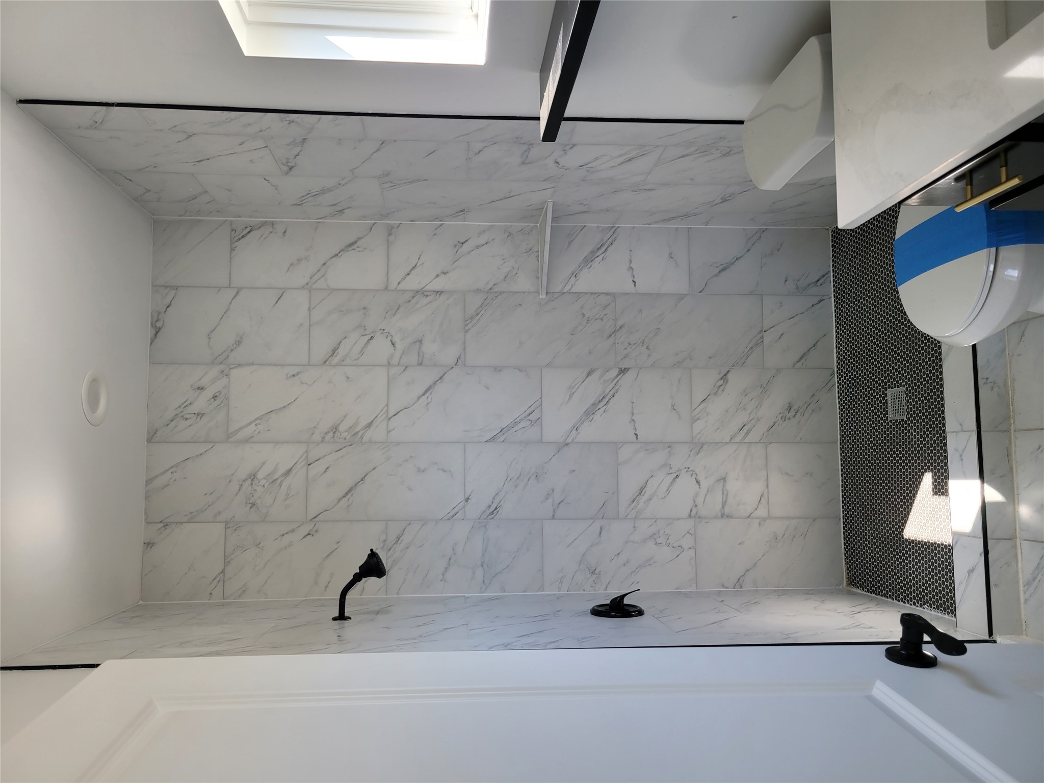 422 A Road Stockdale, TX 78160 - Photo 20 of 40 A pristine bathroom features marble-look tiled shower and sleek dark fixtures, offering a clean, contemporary aesthetic.