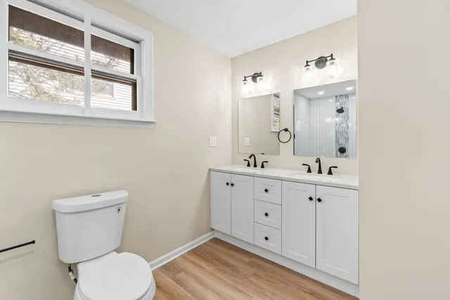 a bathroom with a toilet a sink a mirror and a window