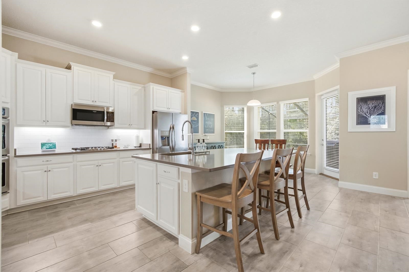 170 Antolin Way St. Augustine, FL 32095 - Photo 19 of 85 Kitchen with hanging light fixtures, a kitchen breakfast bar, white cabinets, crown molding, and a center island with sink