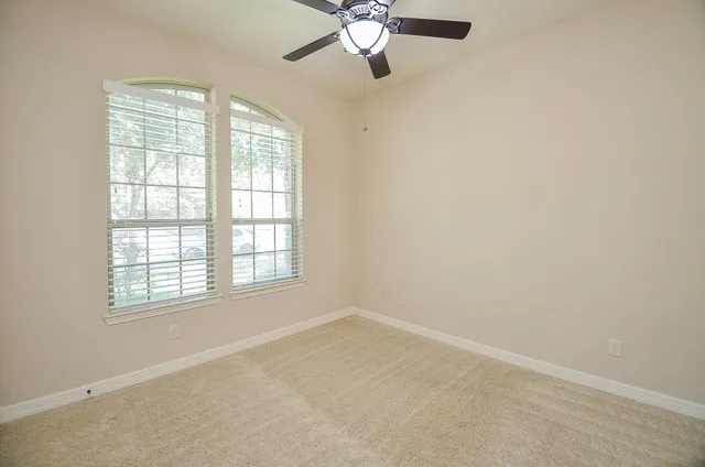 an empty room with a window and a fan