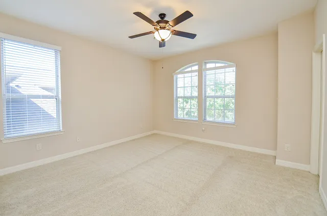 an empty room with windows and fan