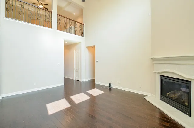 a view of an empty room with wooden floor and a fireplace