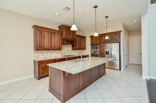 a kitchen with stainless steel appliances granite countertop a sink a oven a counter space and cabinets