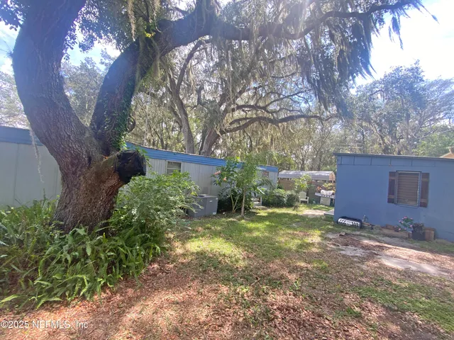 a view of a yard in front of a house with large trees and plants
