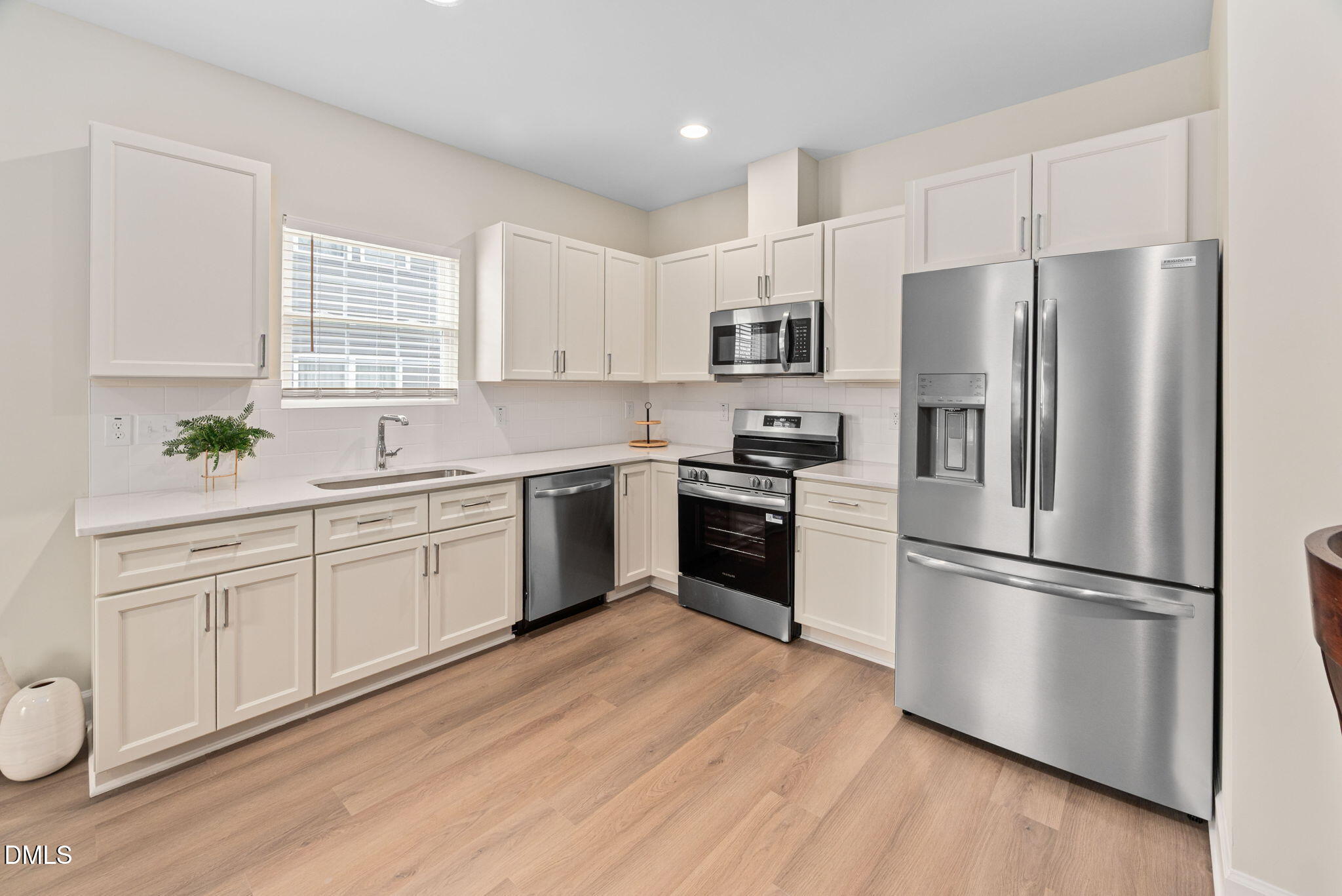 1106 South Blount Street Raleigh, NC 27601 - Photo 3 of 33 a kitchen with white cabinets stainless steel appliances and window