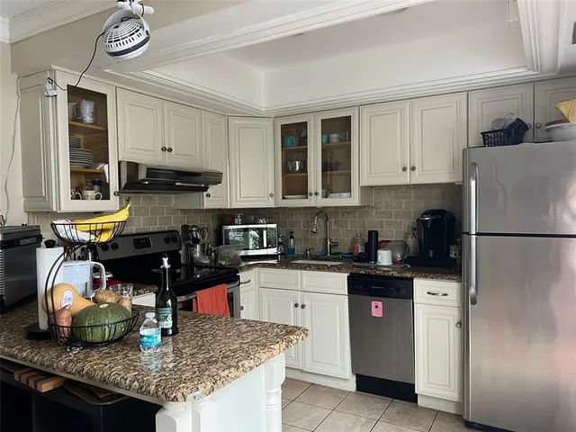 a kitchen with kitchen island granite countertop a sink a stove and refrigerator