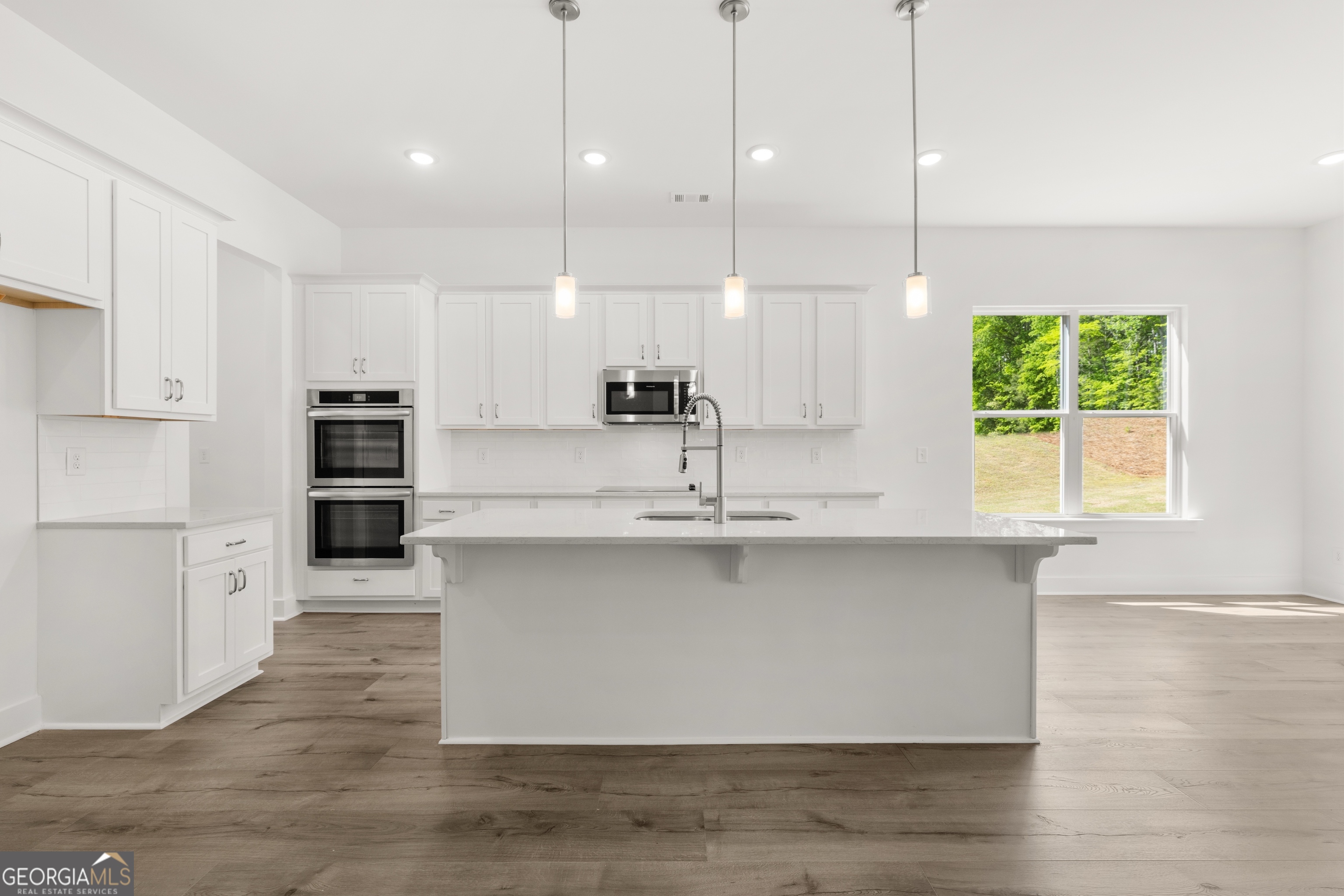 15 Overview Court Hoschton, GA 30548 - Photo 12 of 43 a large kitchen with stainless steel appliances granite countertop a sink a oven a refrigerator and a granite counter tops with wooden floors