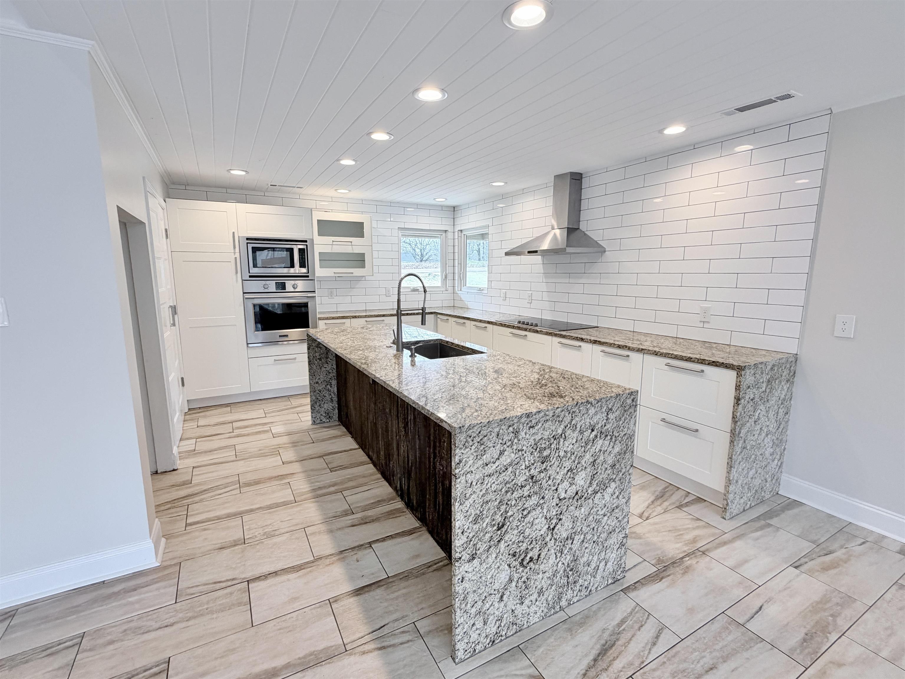 955 Country Club Road Somerville, TN 38068 - Photo 14 of 40 Kitchen featuring light stone countertops, stainless steel appliances, white cabinetry, an island with sink, and tasteful backsplash