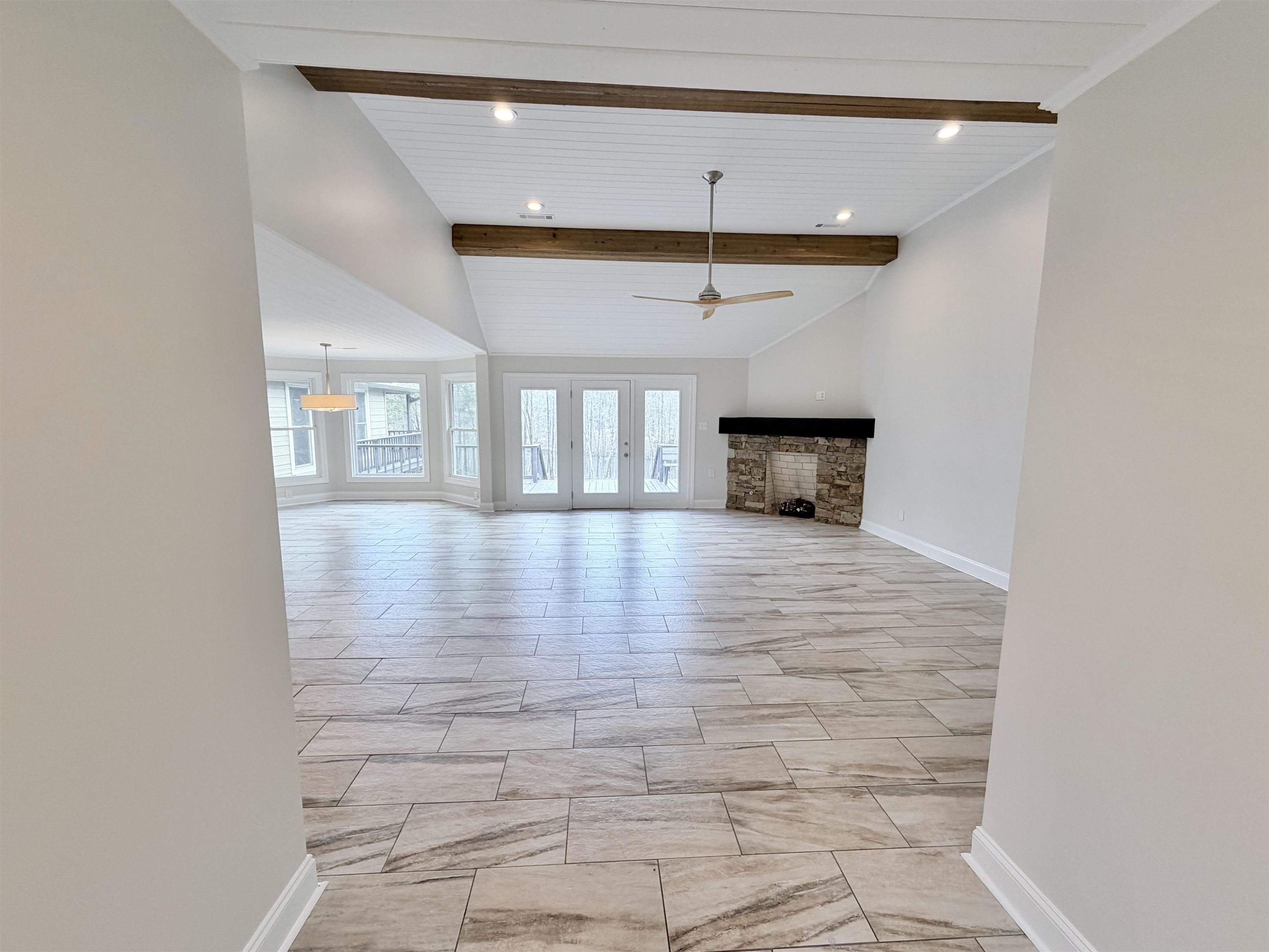 955 Country Club Road Somerville, TN 38068 - Photo 7 of 40 Unfurnished living room with vaulted ceiling with beams, a ceiling fan, french doors, a stone fireplace, and recessed lighting