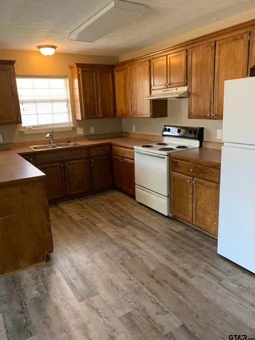 a kitchen with granite countertop a stove a sink dishwasher and a refrigerator