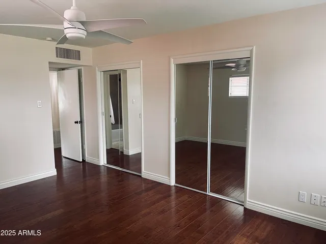 an empty room with wooden floor closet and windows