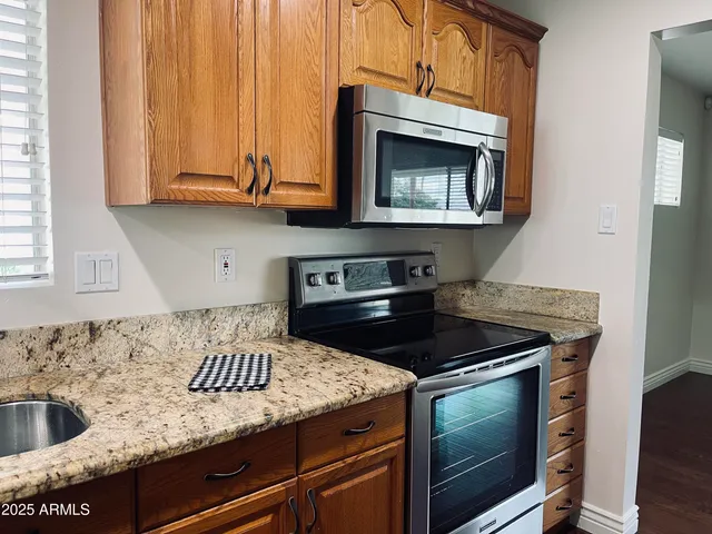 a kitchen with granite countertop stainless steel appliances a stove and a microwave