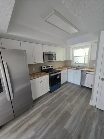 a large kitchen with cabinets wooden floor and stainless steel appliances
