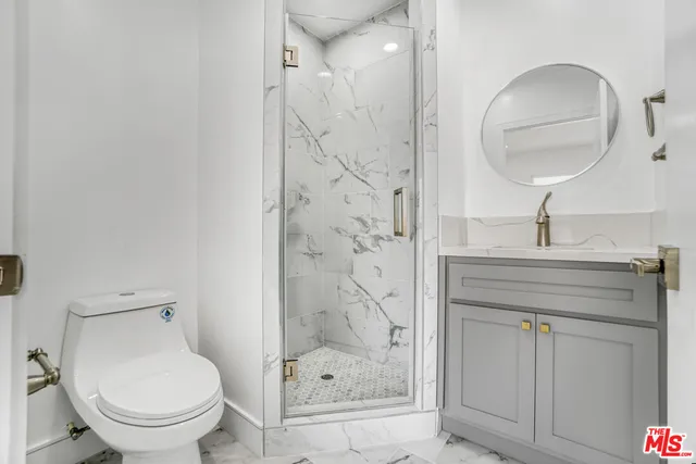 a bathroom with a granite countertop toilet a sink a mirror and shower