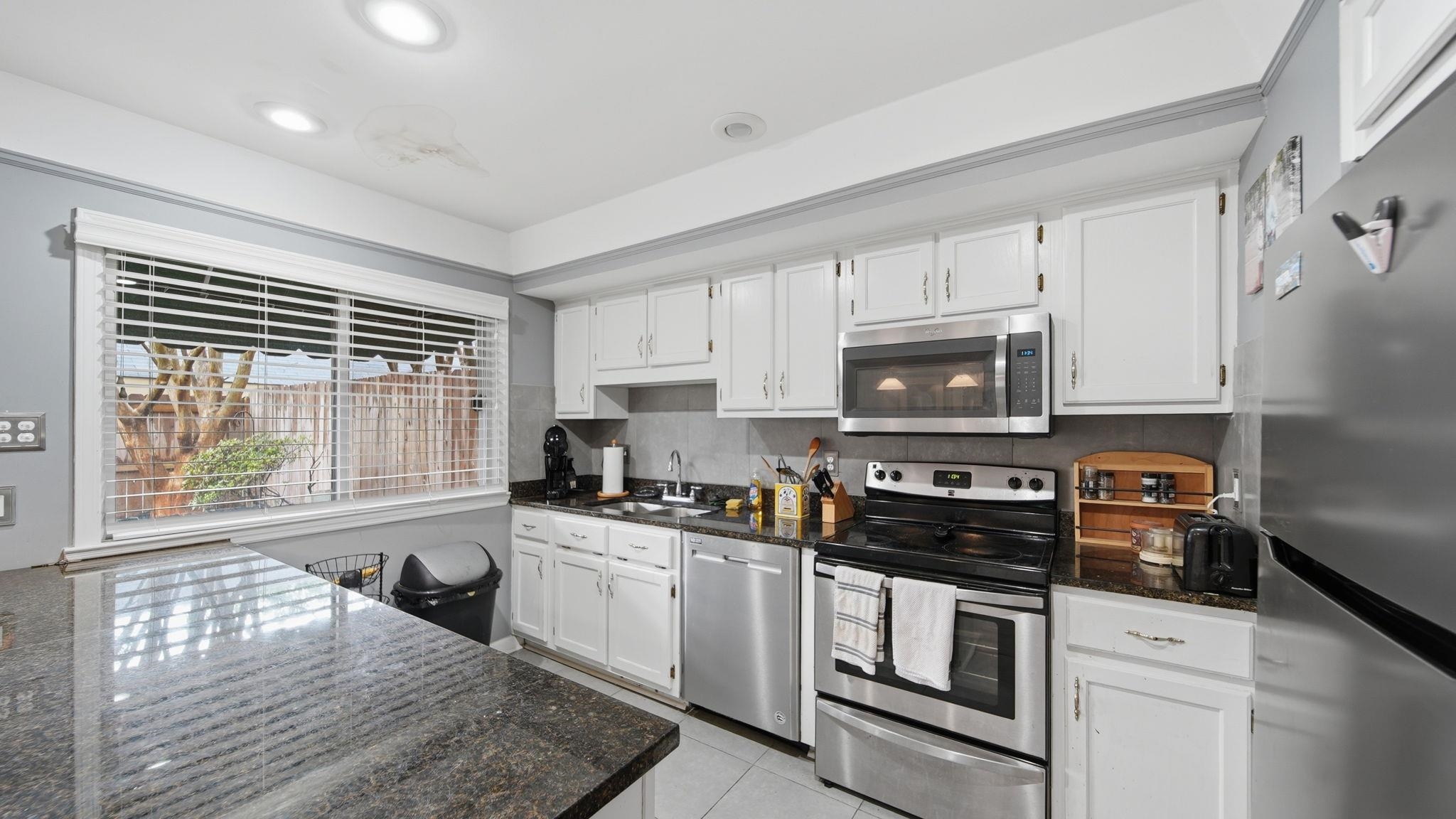 5866 Roxbury Drive, Unit 5866 Memphis, TN 38119 - Photo 10 of 20 Kitchen featuring white cabinetry, dark granite countertops, stainless steel appliances, and tile flooring