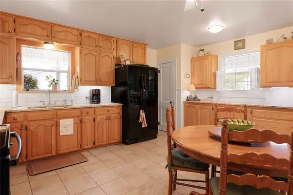 a kitchen with stainless steel appliances granite countertop a refrigerator a sink dishwasher a dining table and chairs with wooden floor