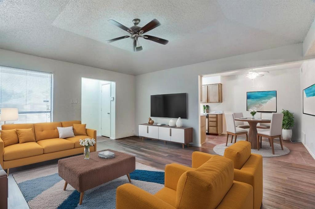 Living area featuring wood finished floors, a textured ceiling, a ceiling fan, and baseboards Virtually Staged