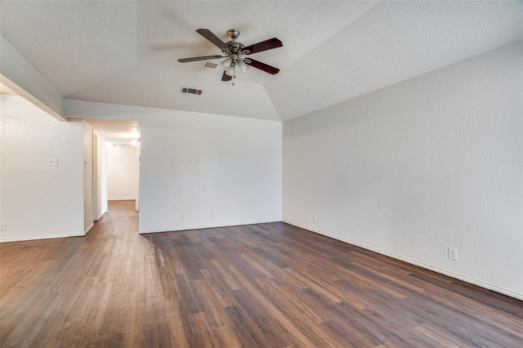 2820 Ridgecrest Drive Fort Worth, TX 76133 - Photo 9 of 25 Spare room featuring ceiling fan, baseboards, dark wood finished floors, lofted ceiling, and visible vents