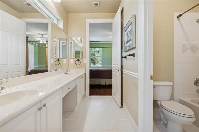 a spacious bathroom with a granite countertop sink mirror vanity and toilet