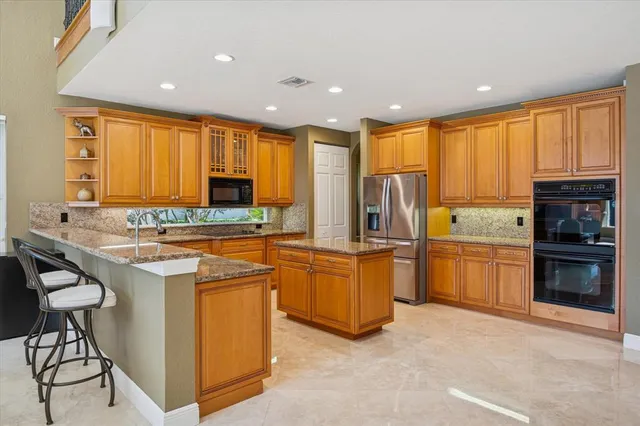 a kitchen with stainless steel appliances granite countertop a stove top oven a sink dishwasher and a refrigerator