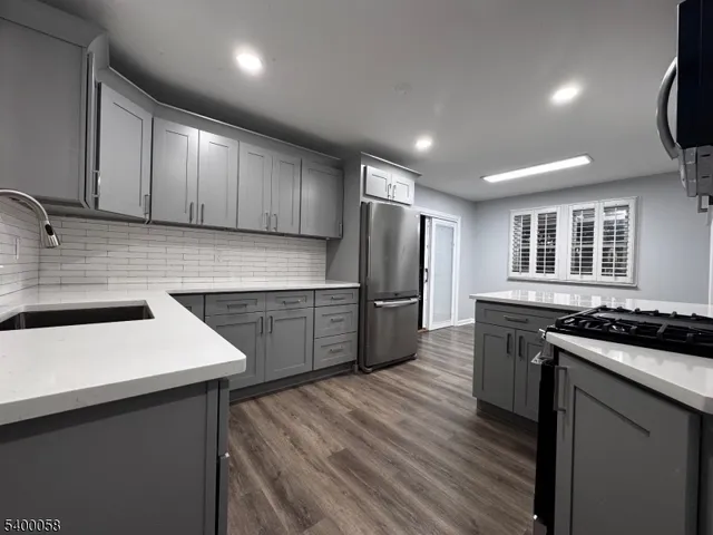 a kitchen with stainless steel appliances granite countertop a sink and stove top oven with wooden floor