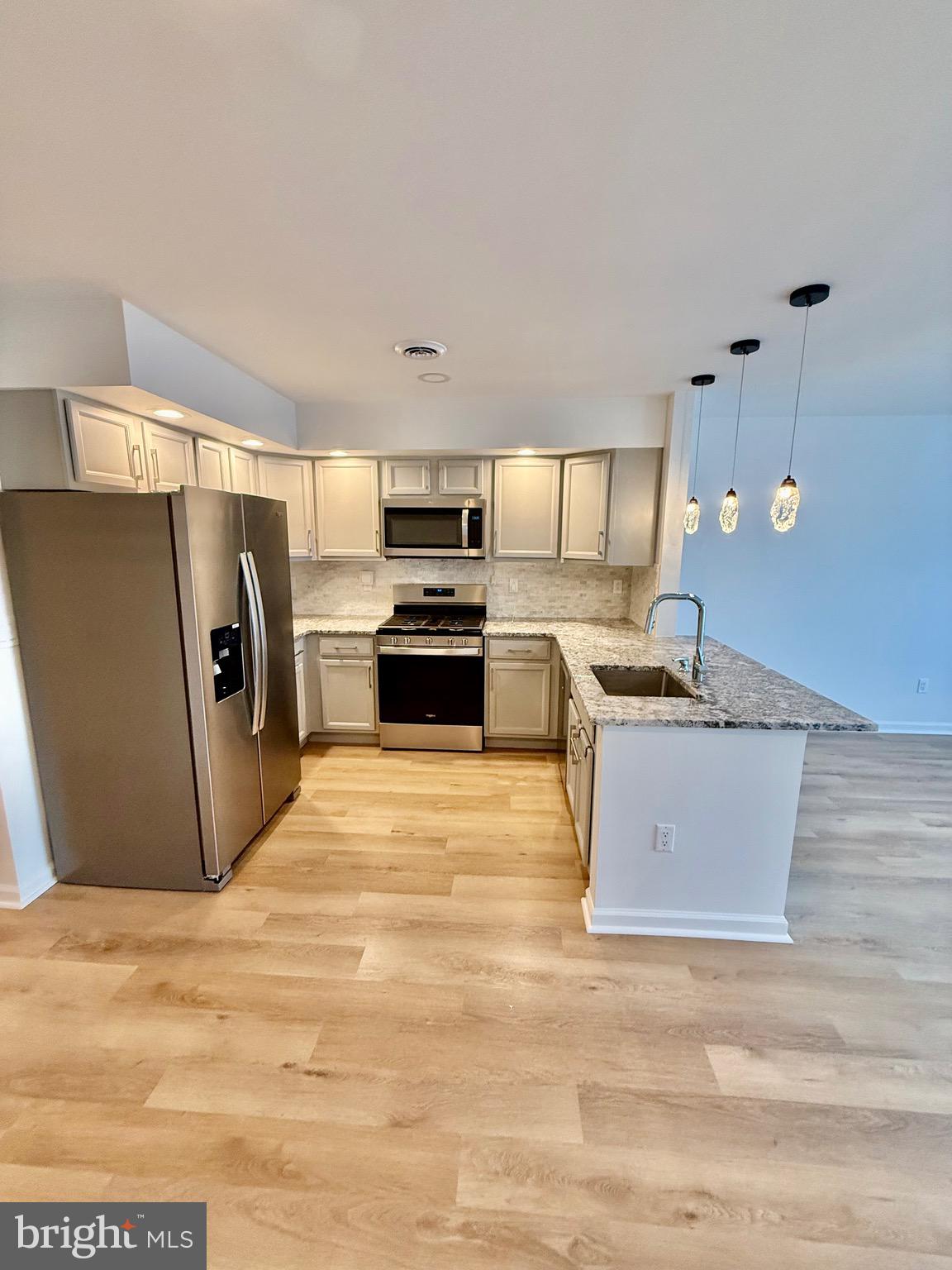 a large white kitchen with stainless steel appliances granite countertop a stove and a refrigerator