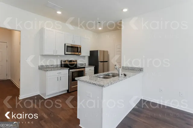 a kitchen with granite countertop a refrigerator stove and a sink