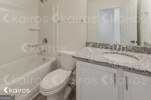 a bathroom with a granite countertop sink a toilet and bathtub