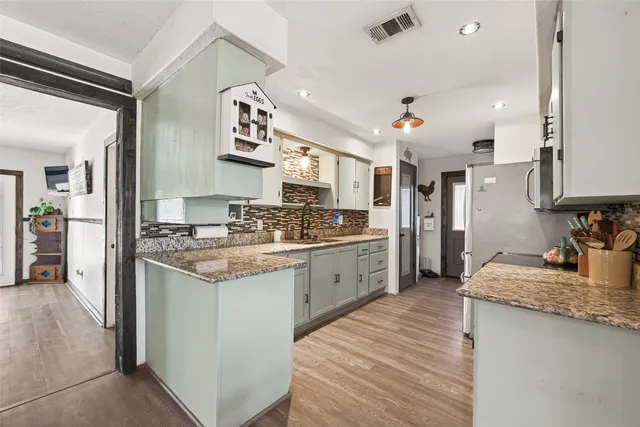 a kitchen with granite countertop a sink stove and refrigerator