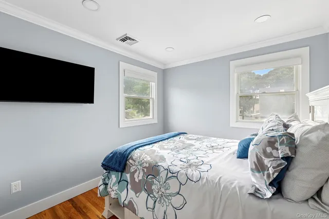 a bedroom with a bed and a flat tv screen on the dresser