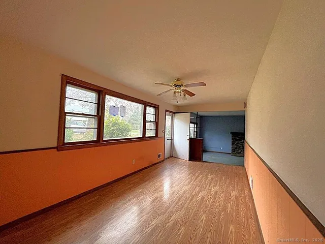a view of empty room with wooden floor and fan