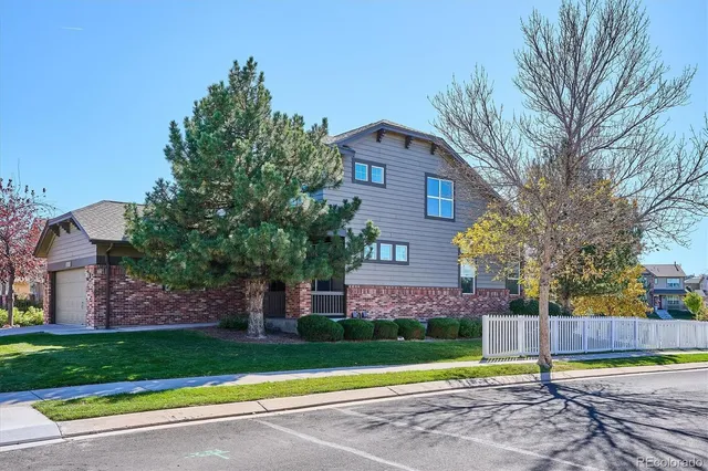 a view of a brick house with a big yard and large trees